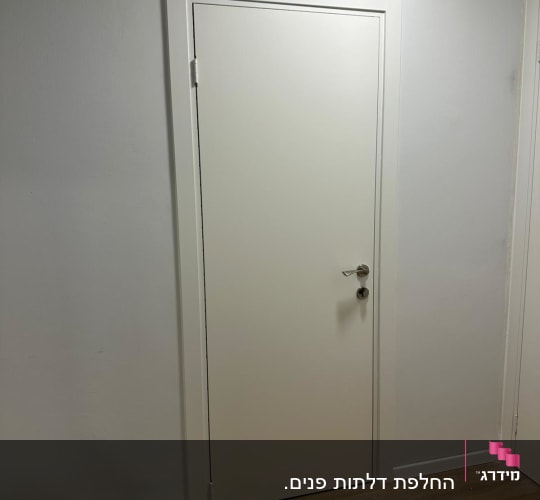 דלת לבנה עם ידית מתכת על קיר לבן